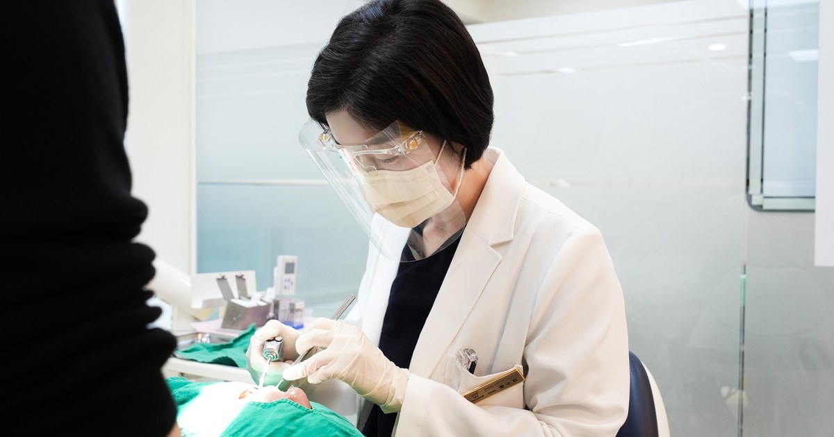 새론이치과 원장님이 환자의 구강 상태를 살펴보는 진료 모습
